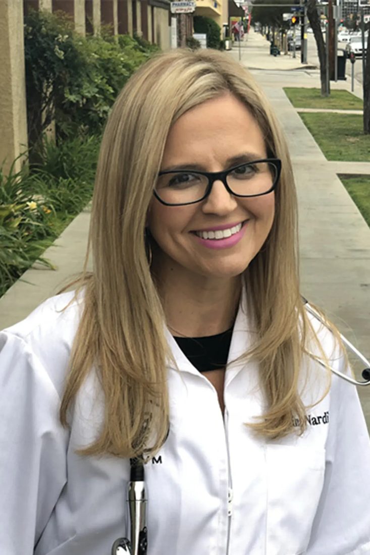 Smiling female veterinarian with glasses and stethoscope outdoors on a sidewalk